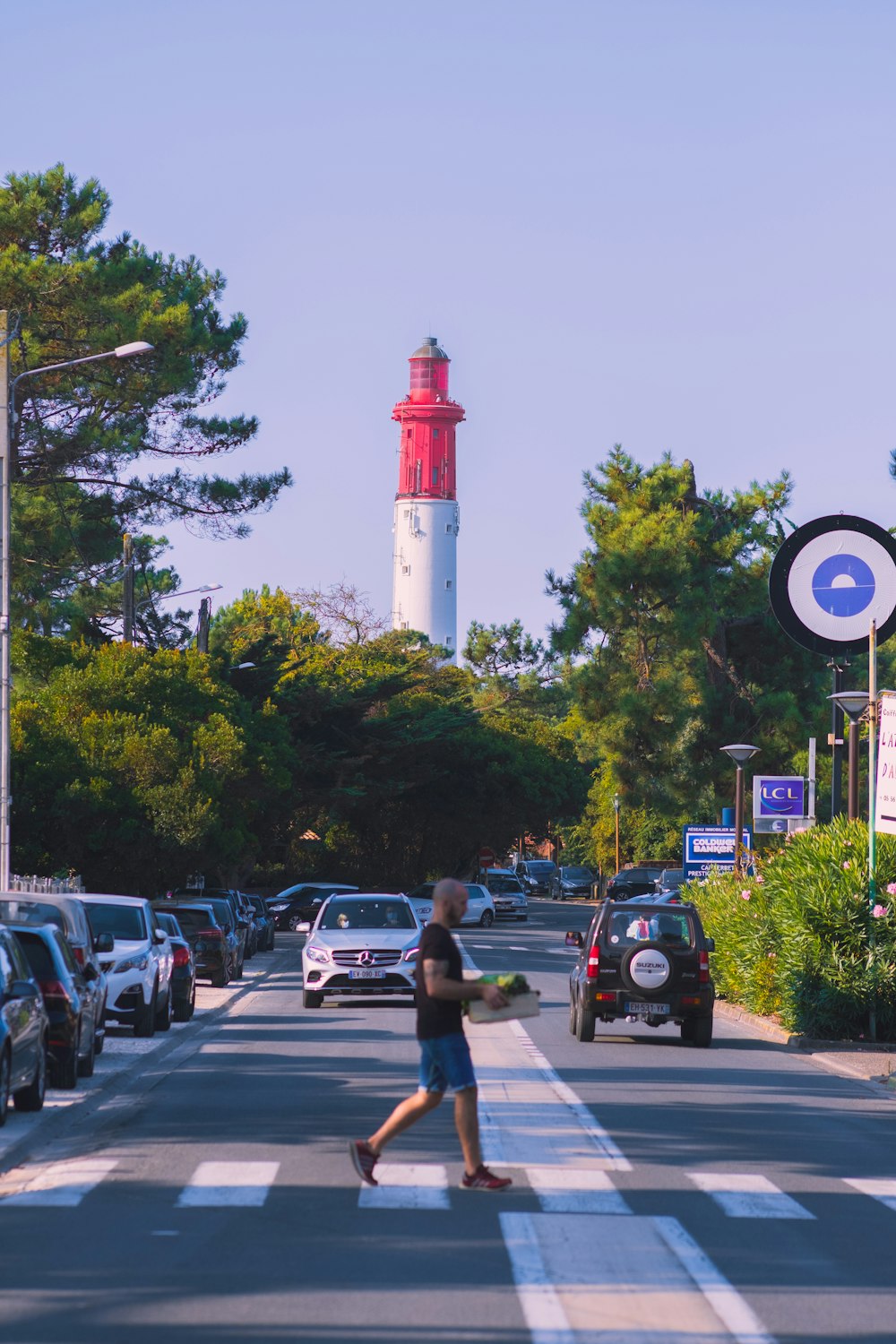 a person crossing a street in front of a light house