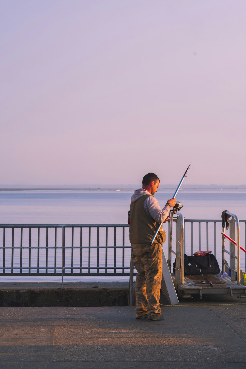 a man standing on a sidewalk holding a fishing pole