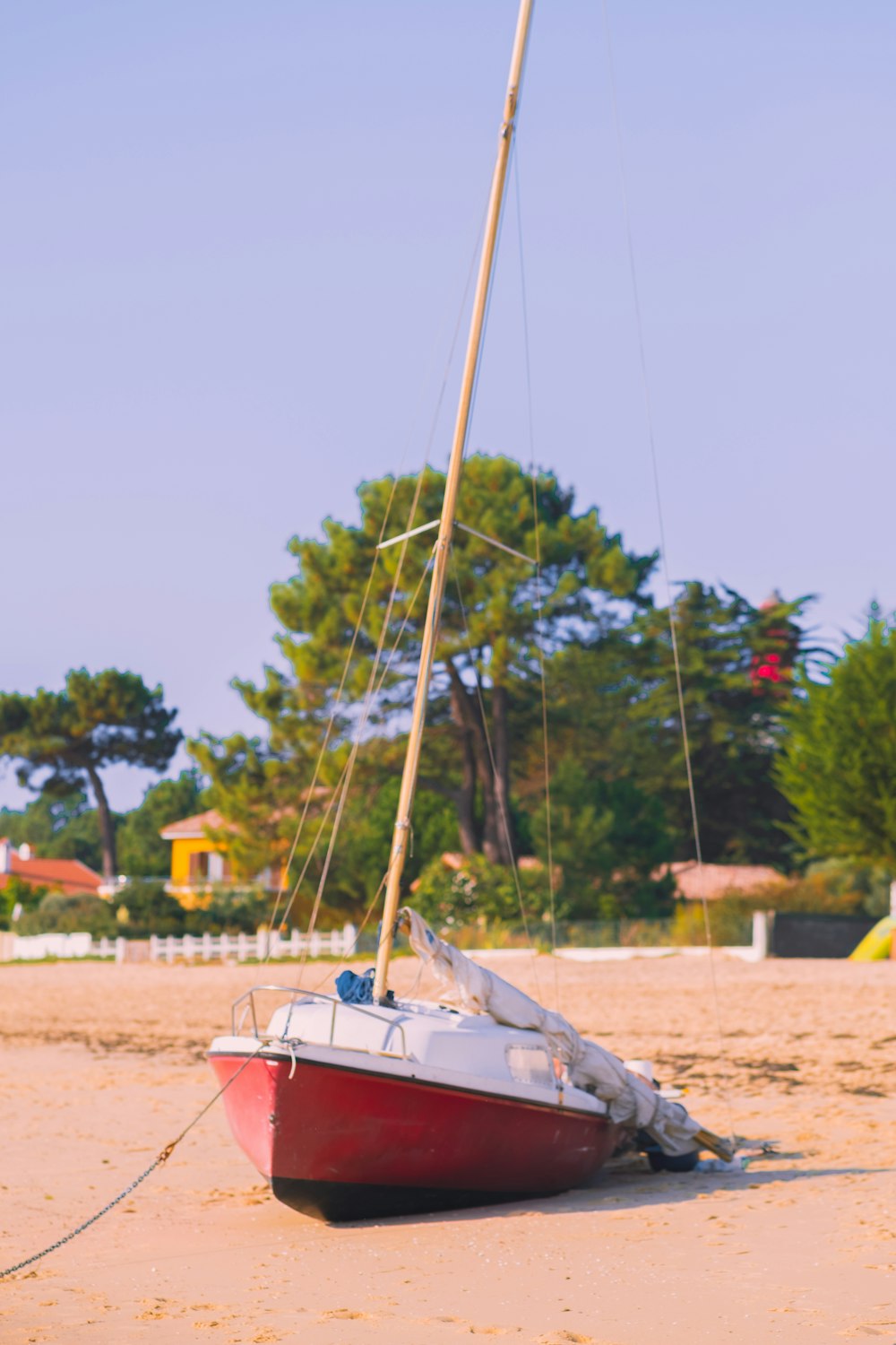 a small sailboat on the beach with trees in the background
