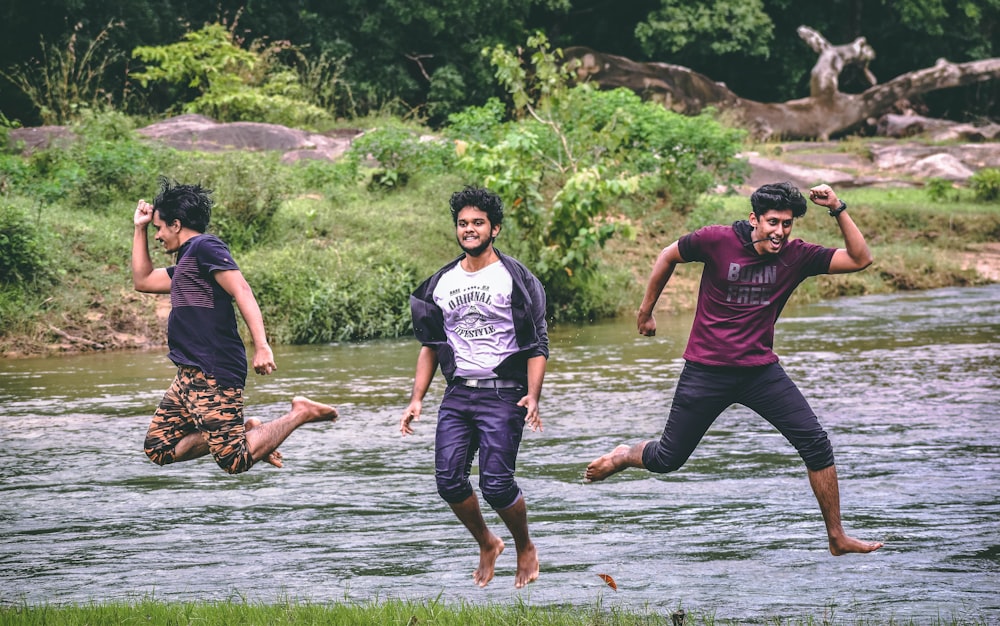 a group of young men jumping into a river
