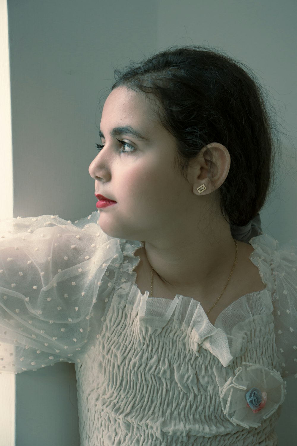 a woman in a white dress looking out a window