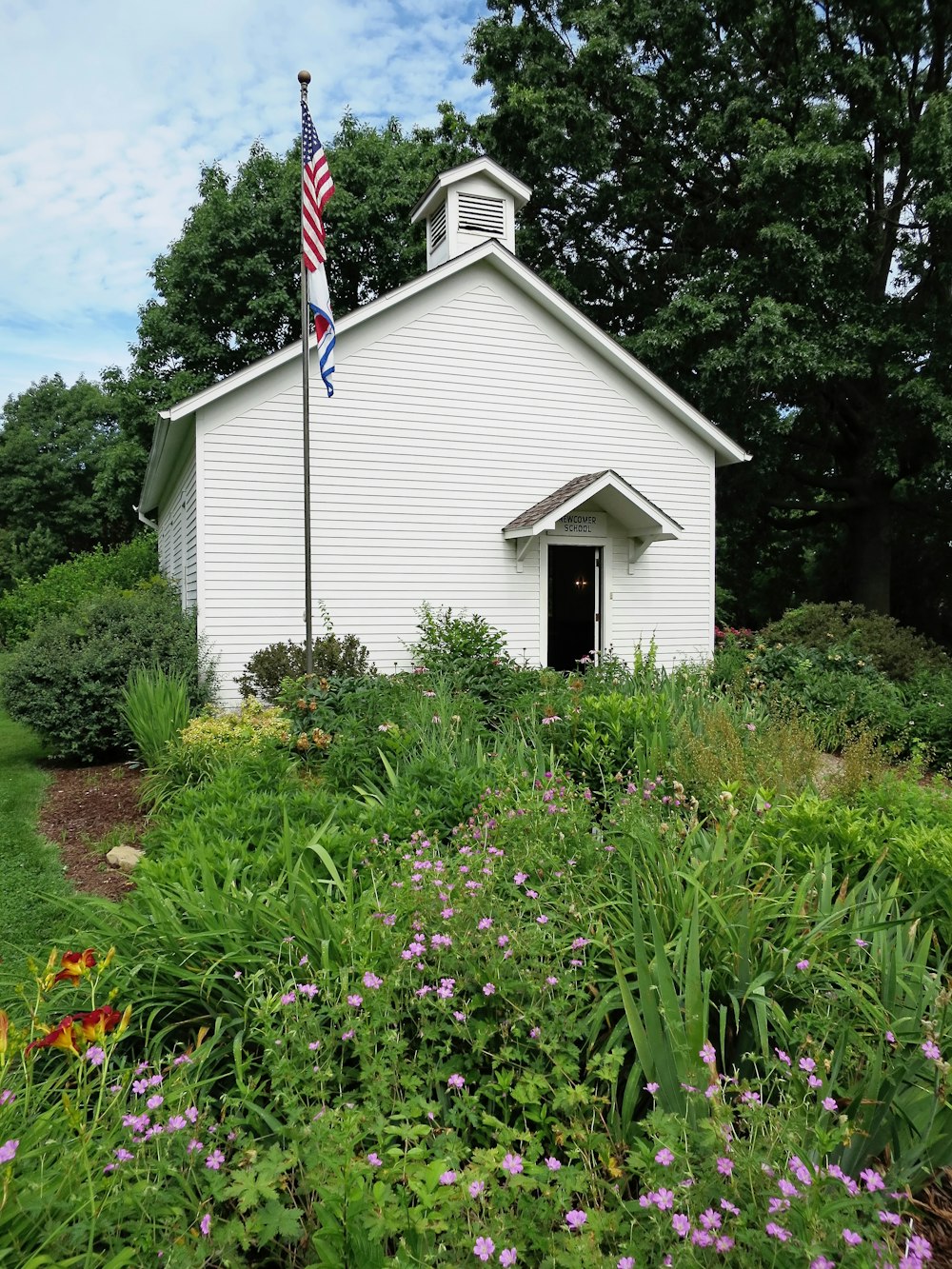a small white church with a flag on top of it