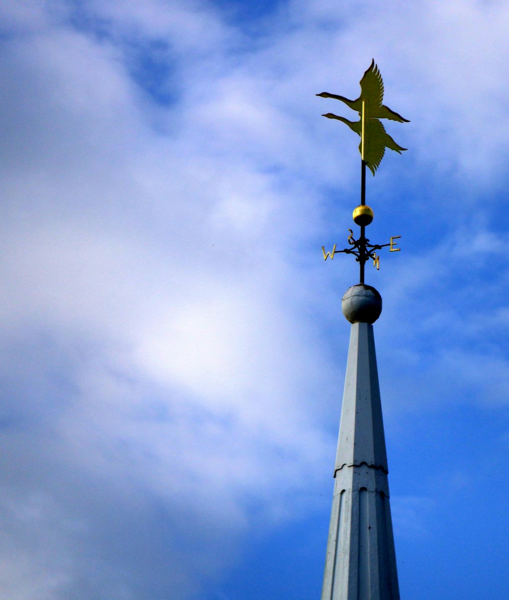 uma torre do relógio alta com um cata-vento no topo