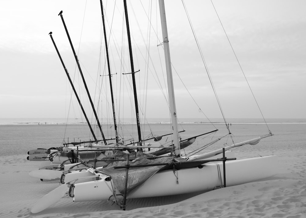 a couple of sail boats sitting on top of a sandy beach