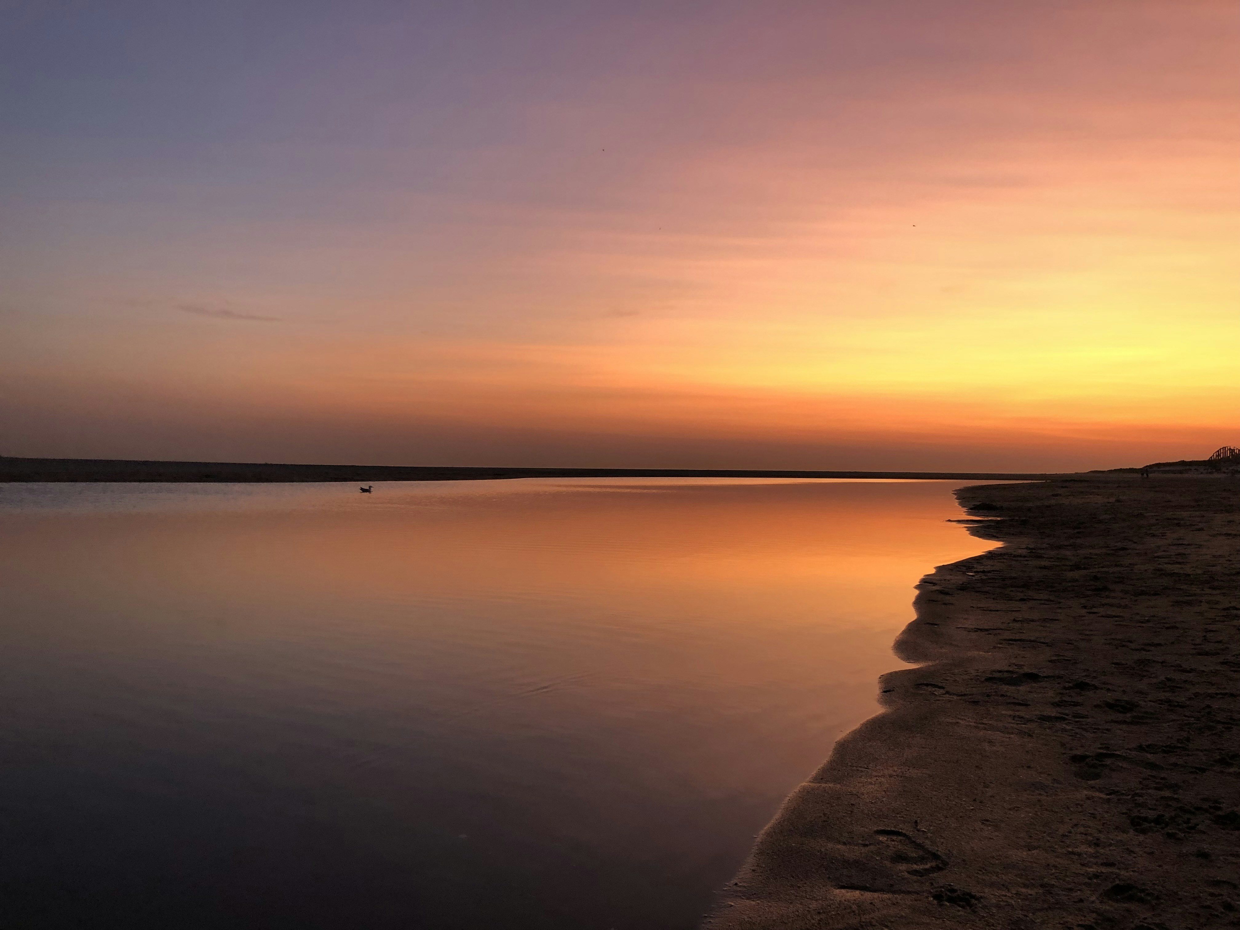 ein Gewässer mit Sonnenuntergang im Hintergrund