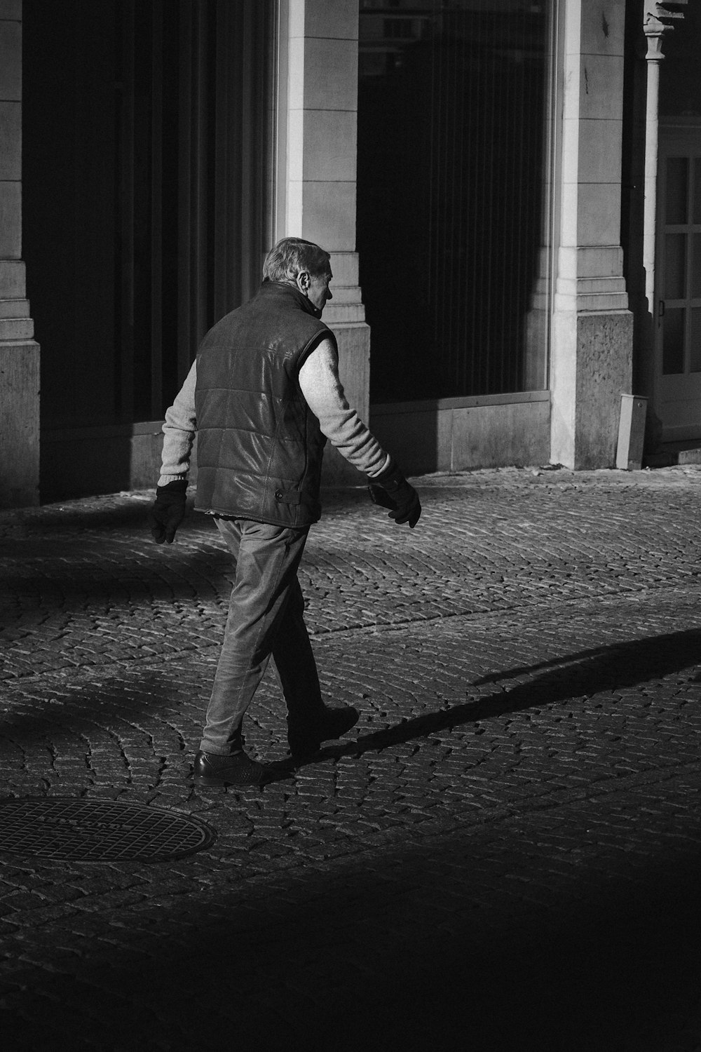 a black and white photo of a man walking down the street