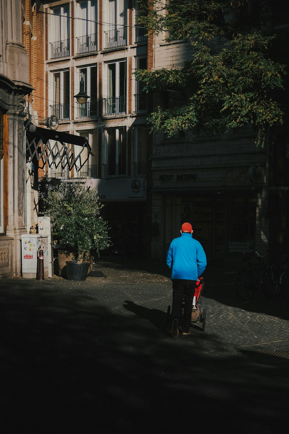 a man in a blue jacket walking down a street