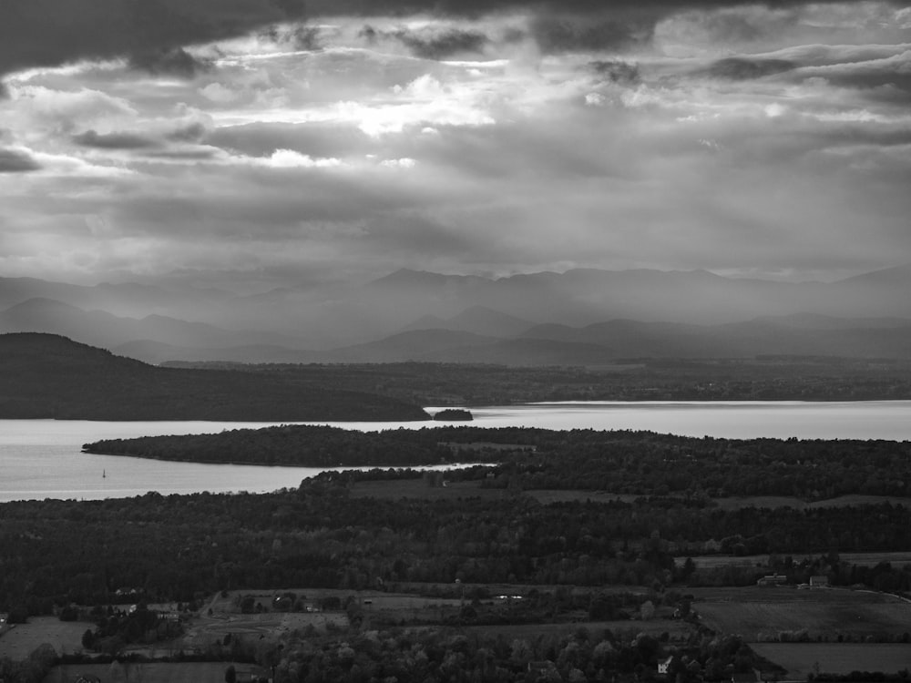 a black and white photo of a lake and mountains