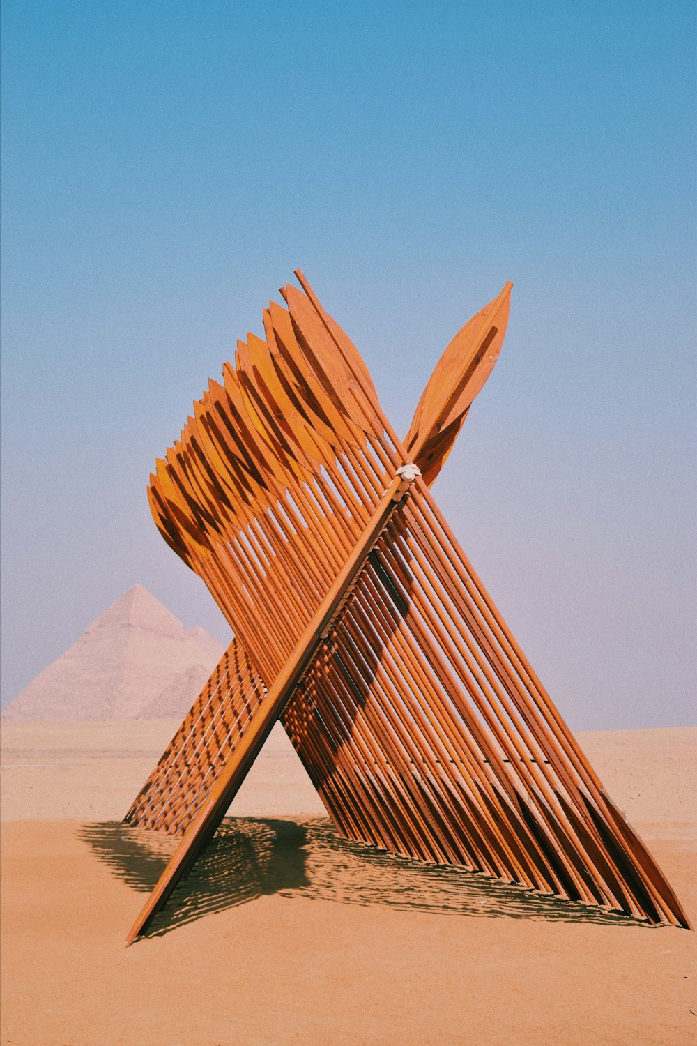 uma grande escultura de madeira sentada no meio de um deserto