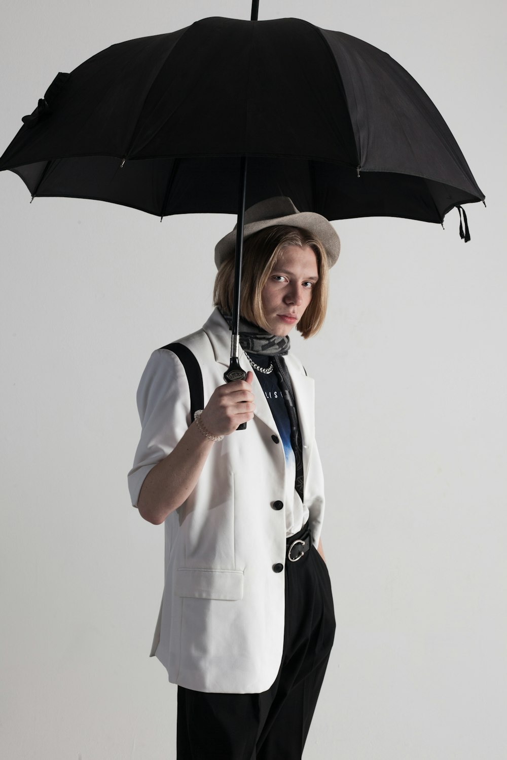 a woman in a suit and hat holding an umbrella