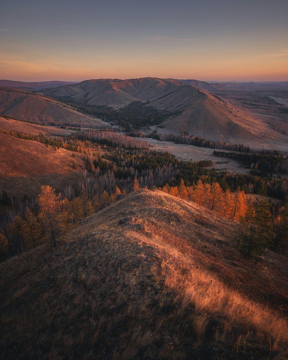 the sun is setting over the hills and trees