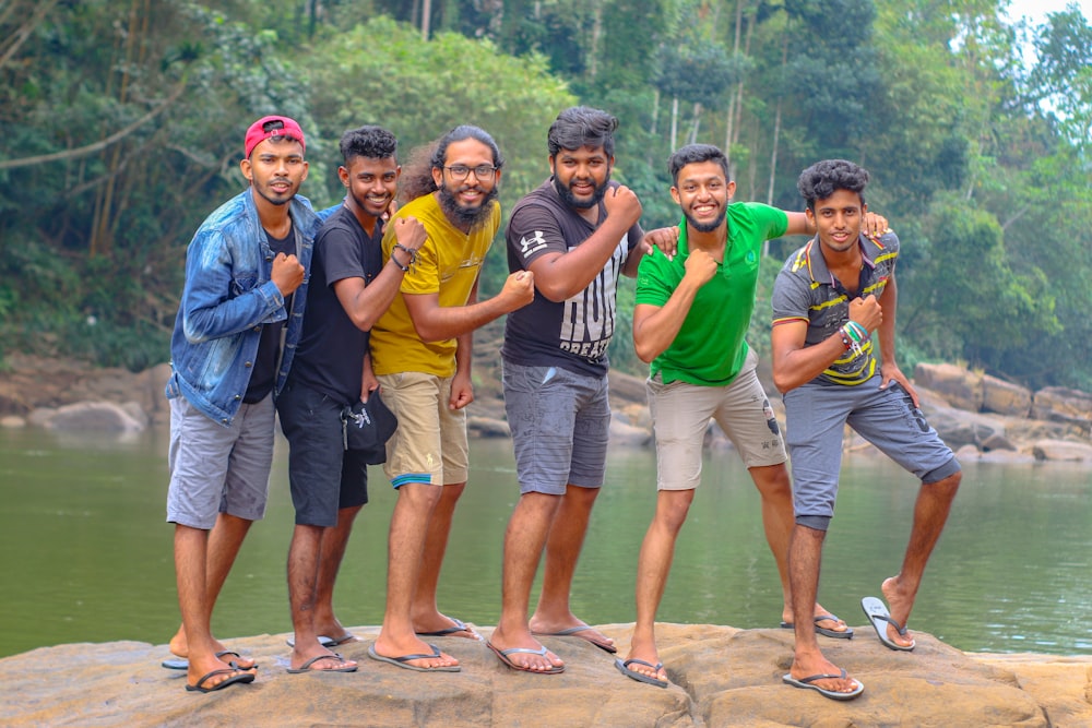 a group of men standing on top of a rock next to a river