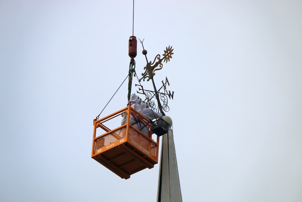 a man on a crane is working on the top of a building