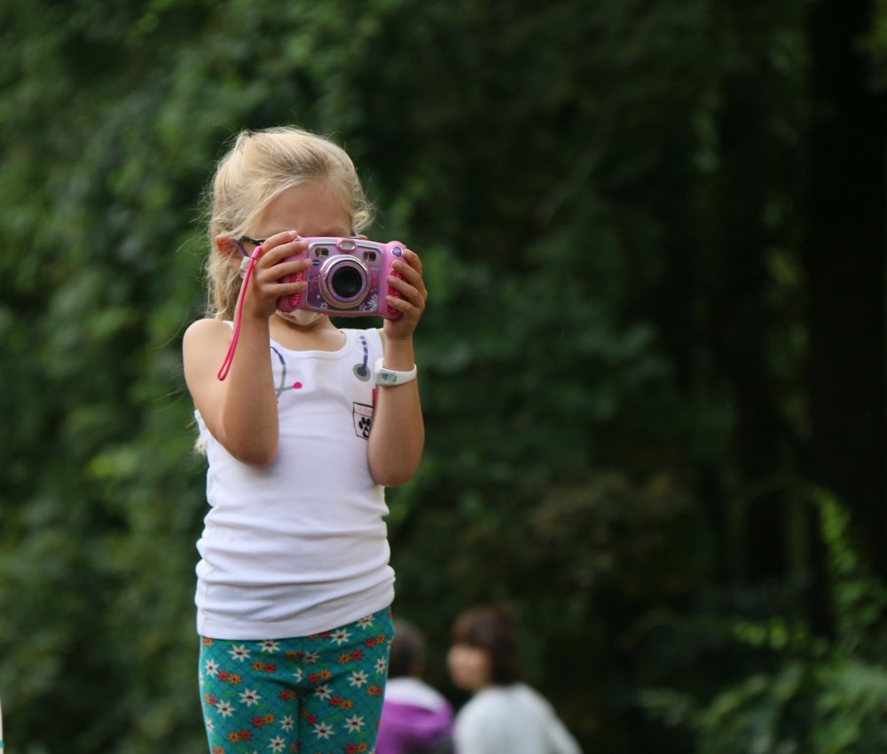 a little girl taking a picture with a camera