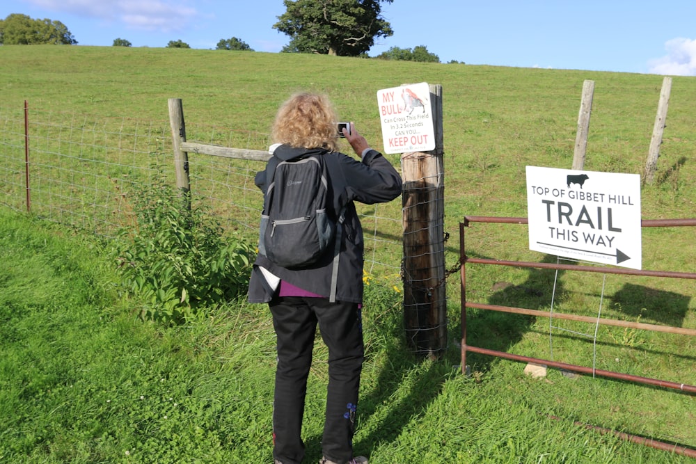 a woman taking a picture of a trail sign