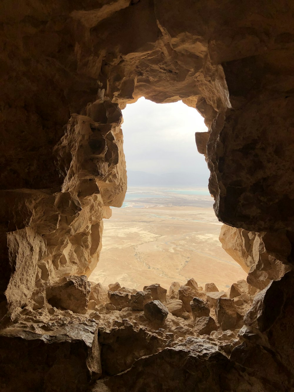 a view of the desert through a hole in a rock wall