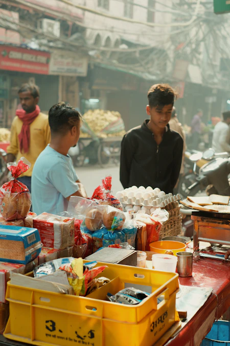 Morning chai and breakfast stall in Old Delhi with men standing beside a table of food