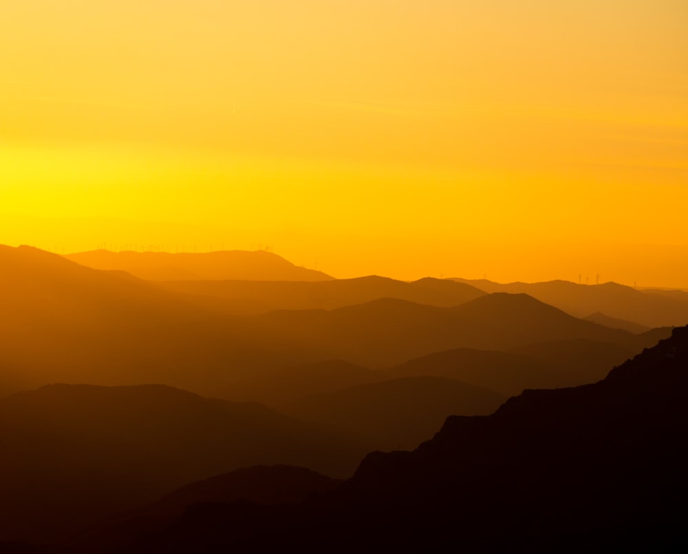 the sun is setting over a mountain range