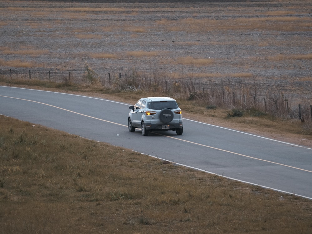 a car driving down a road in the middle of a field