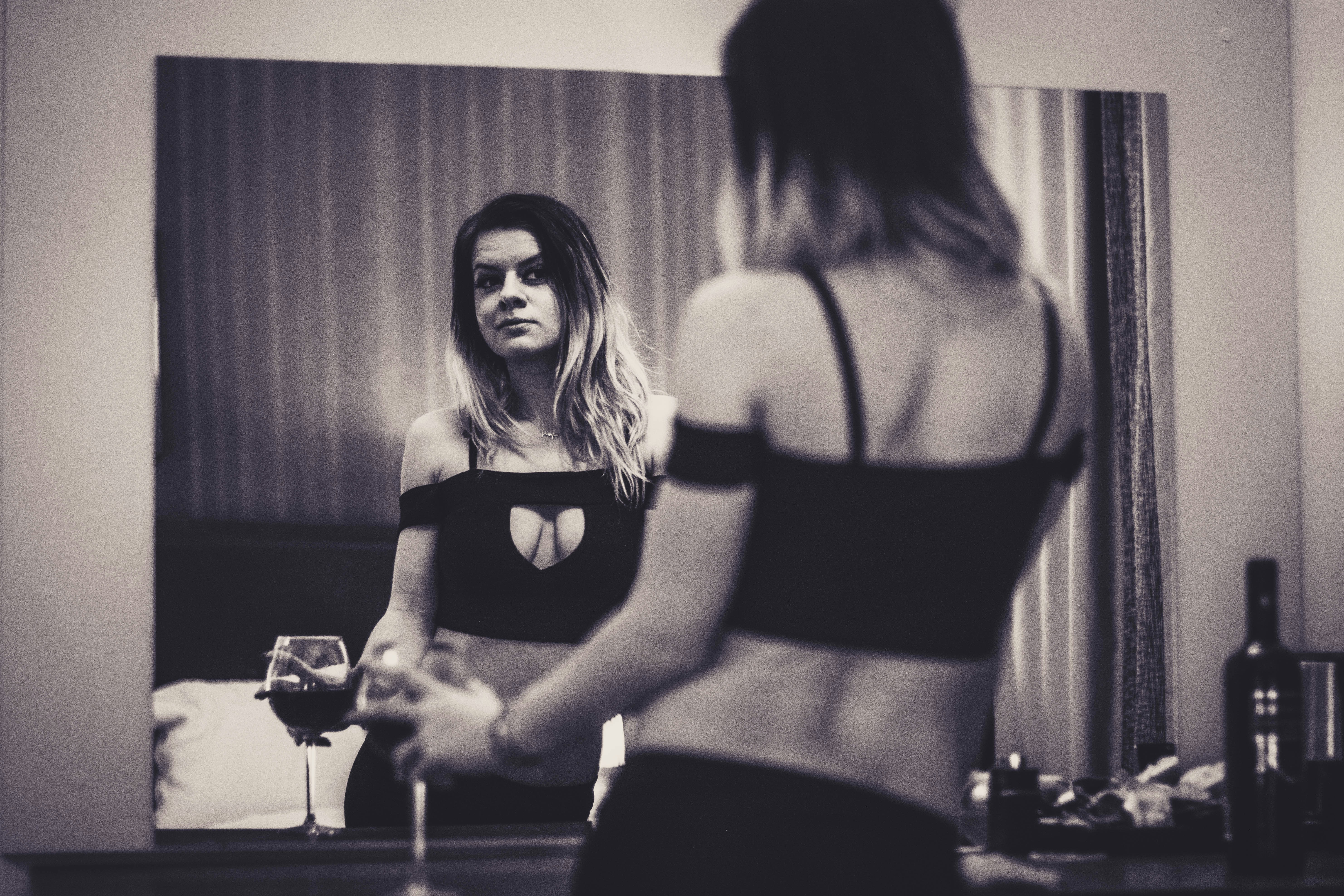 a woman standing in front of a mirror holding a wine glass