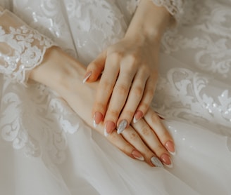 a close up of a person's hands on a wedding dress