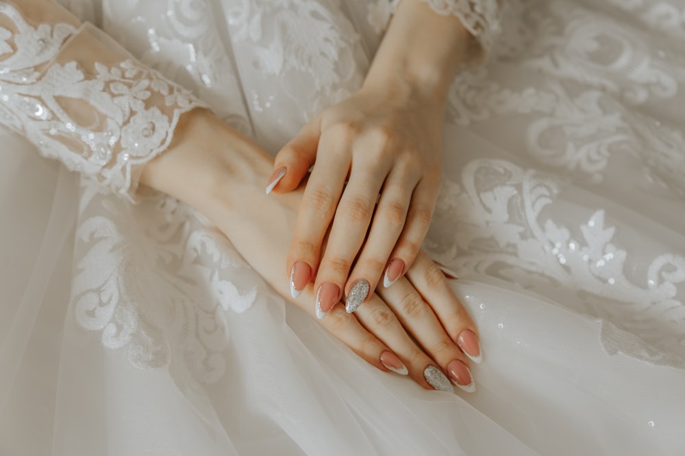 a close up of a person's hands on a wedding dress