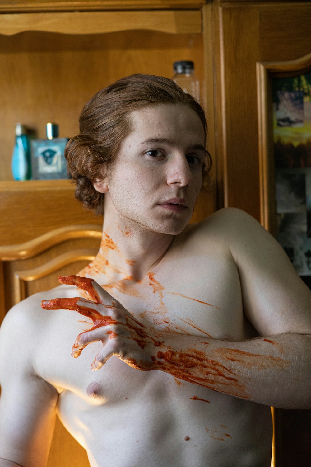 a shirtless man is holding a knife with blood all over his body