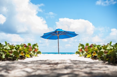 a blue umbrella sitting on top of a sandy beach
