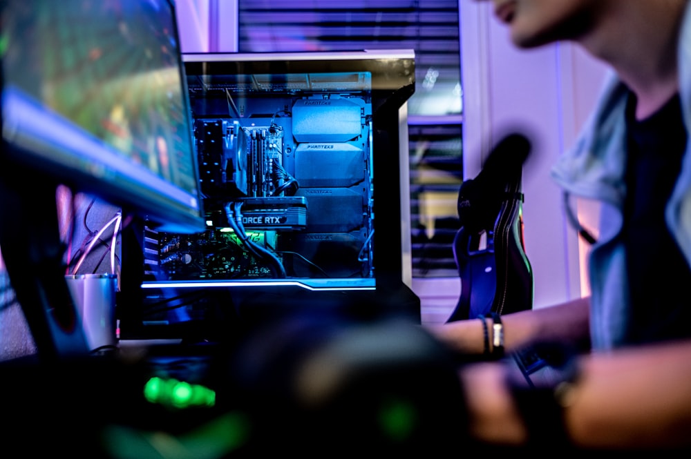 um homem sentado na frente de um monitor de computador