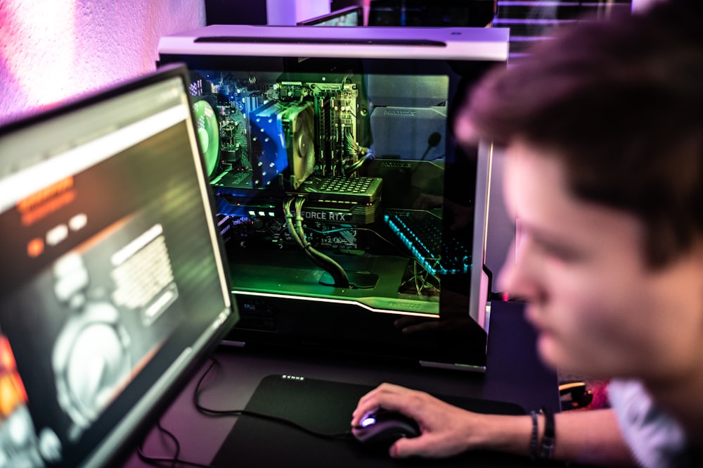 um homem sentado na frente de um monitor de computador