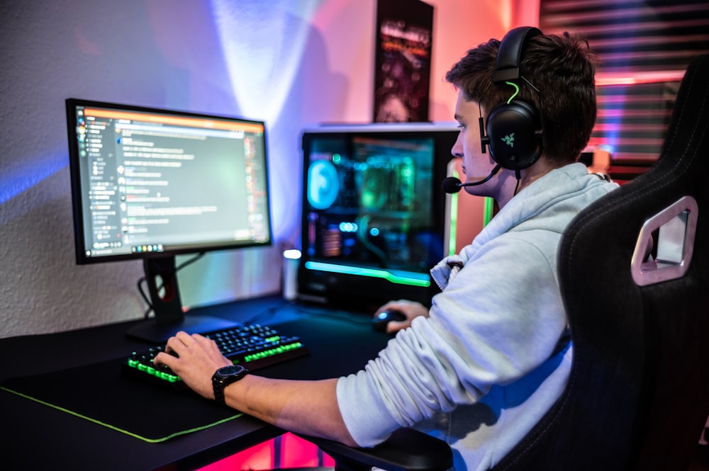 Un hombre sentado frente a una computadora con auriculares puestos