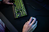 Close-up of a gamer’s hands expertly using a keyboard and mouse with glowing cheat interface overlay.