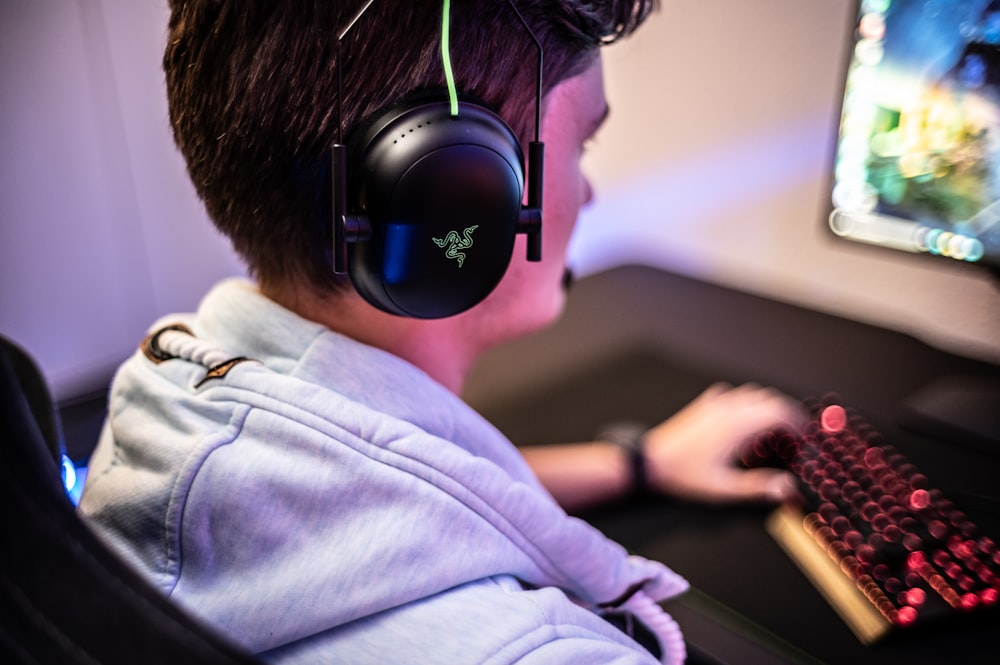 a young boy wearing headphones and using a computer
