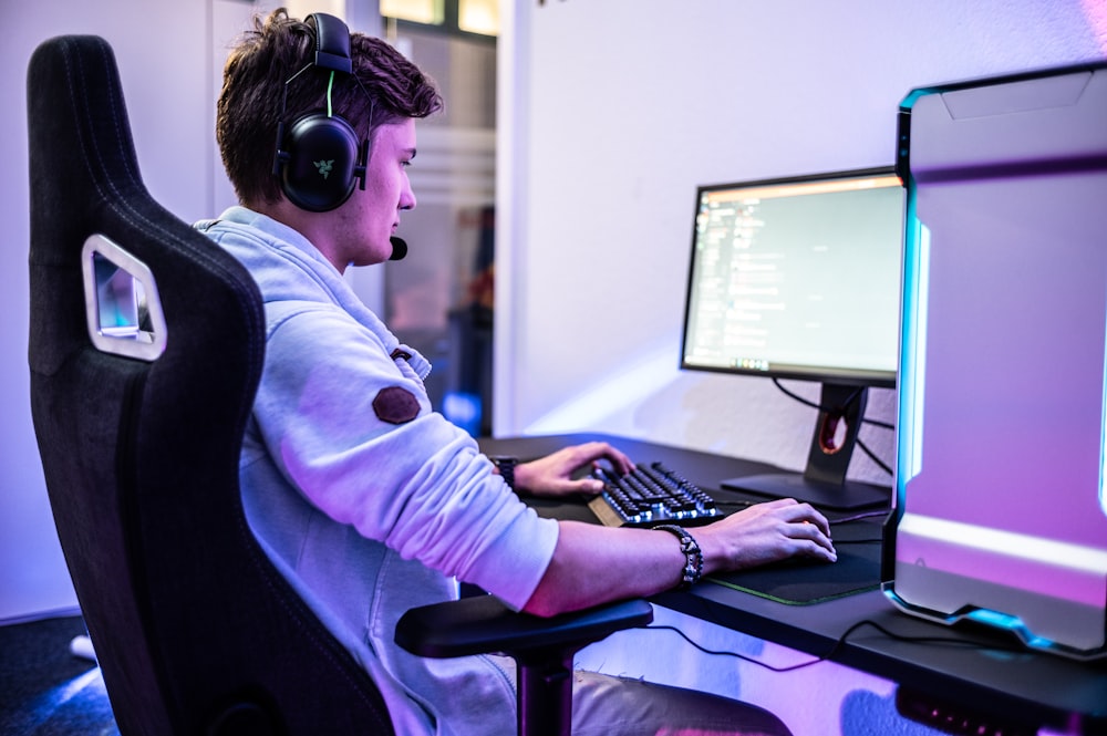 Un joven con auriculares sentado frente a una computadora