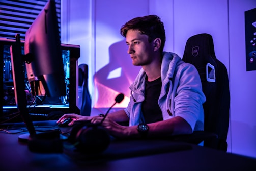 Photo of a gamer focused on a screen with blue and yellow lighting.