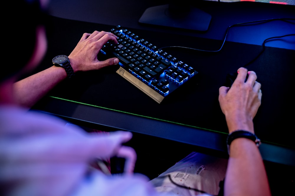 Un hombre está escribiendo en el teclado de una computadora