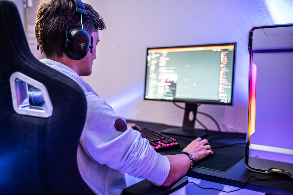 a man wearing headphones sitting in front of a computer