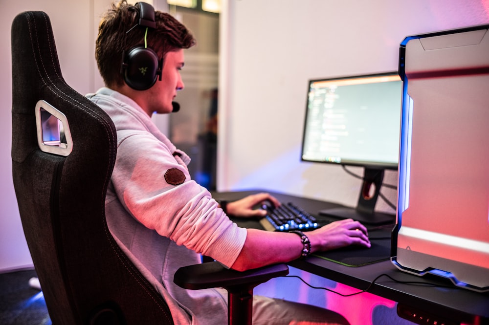 Un hombre sentado frente a una computadora con auriculares puestos