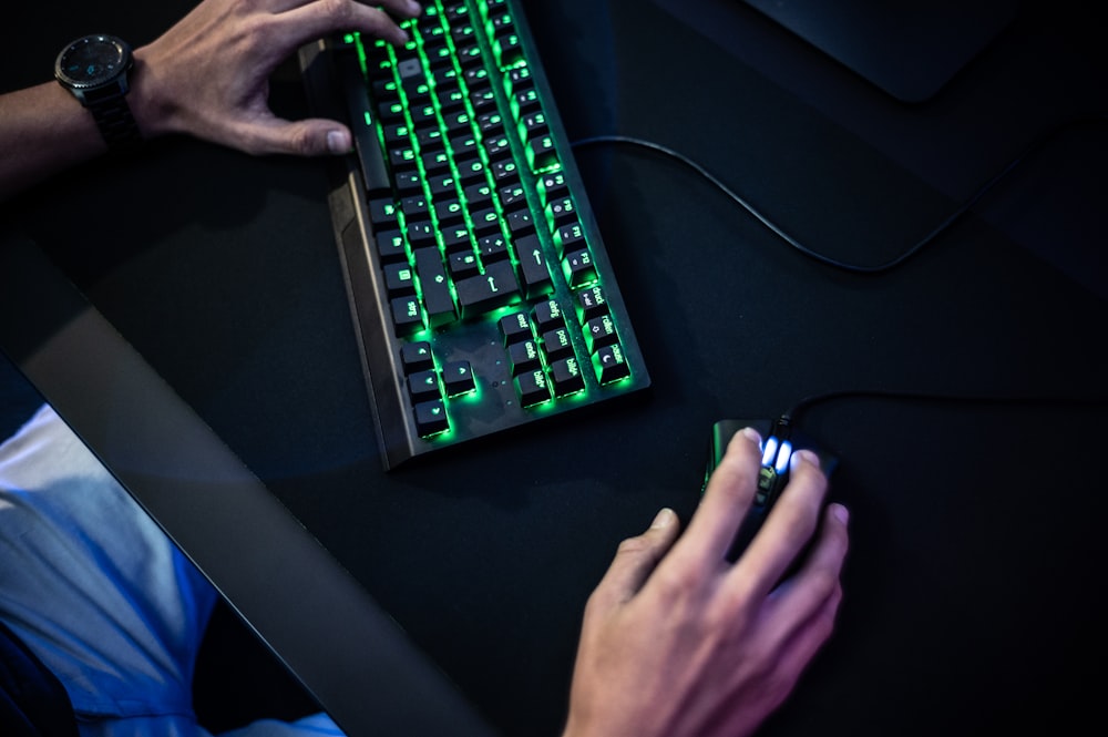 a person typing on a keyboard with a green light