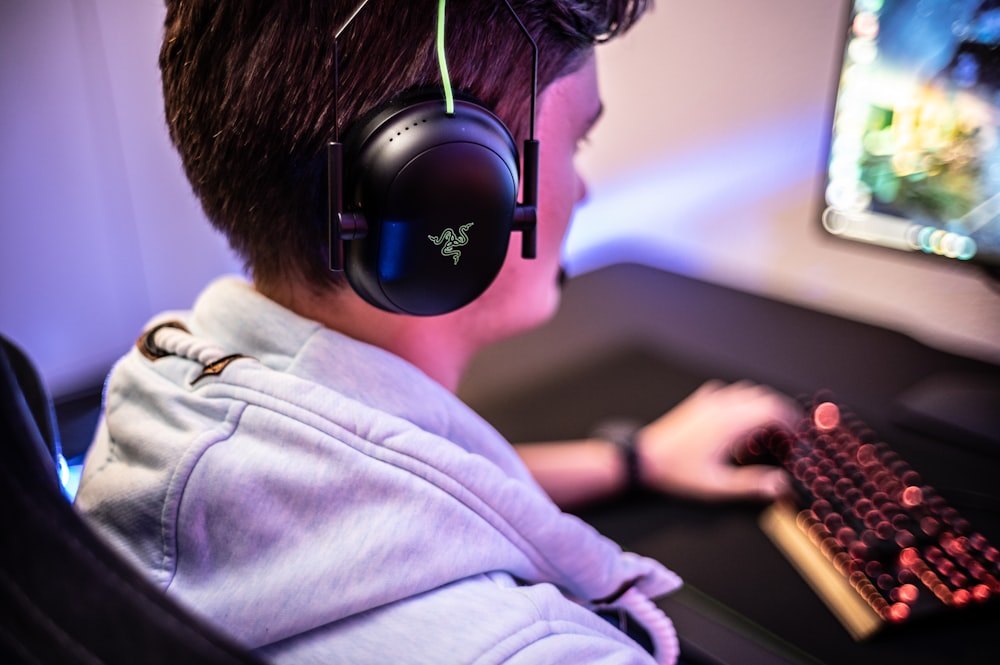 a young boy wearing headphones and using a computer