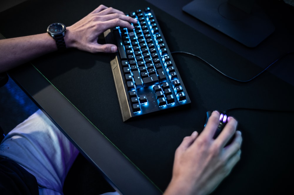 a person typing on a keyboard with a blue light