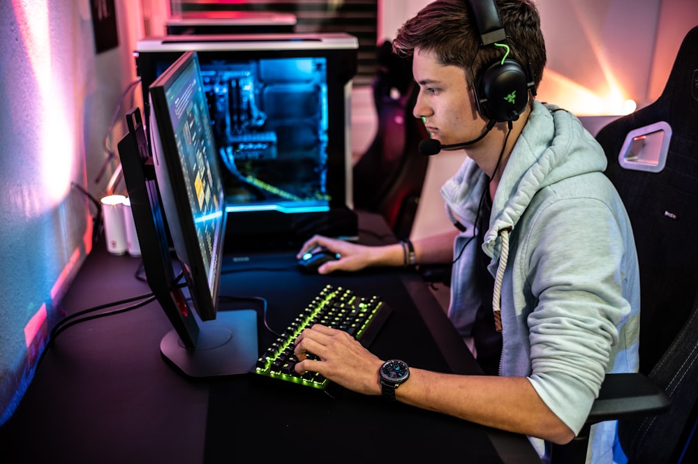 Un hombre sentado frente a una computadora con auriculares puestos