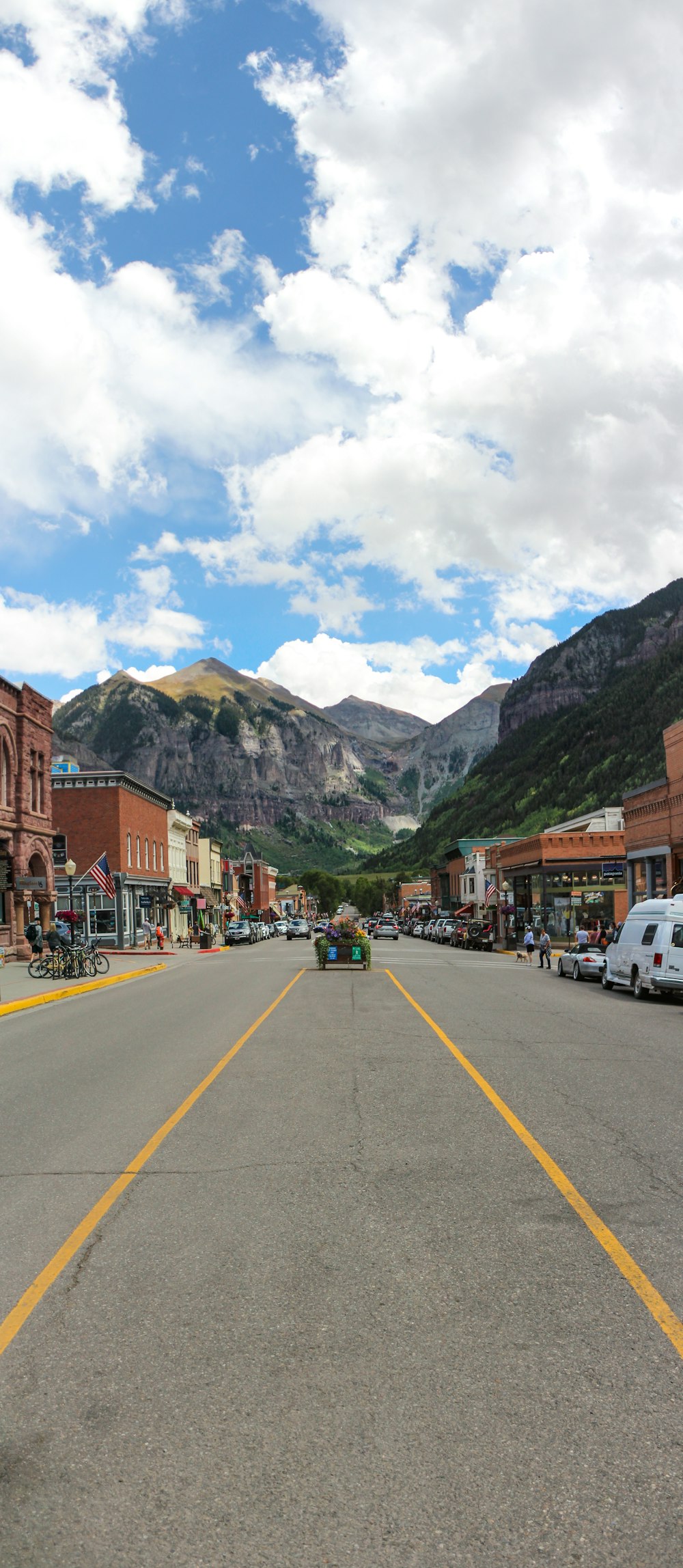 a street lined with buildings and mountains under a cloudy sky