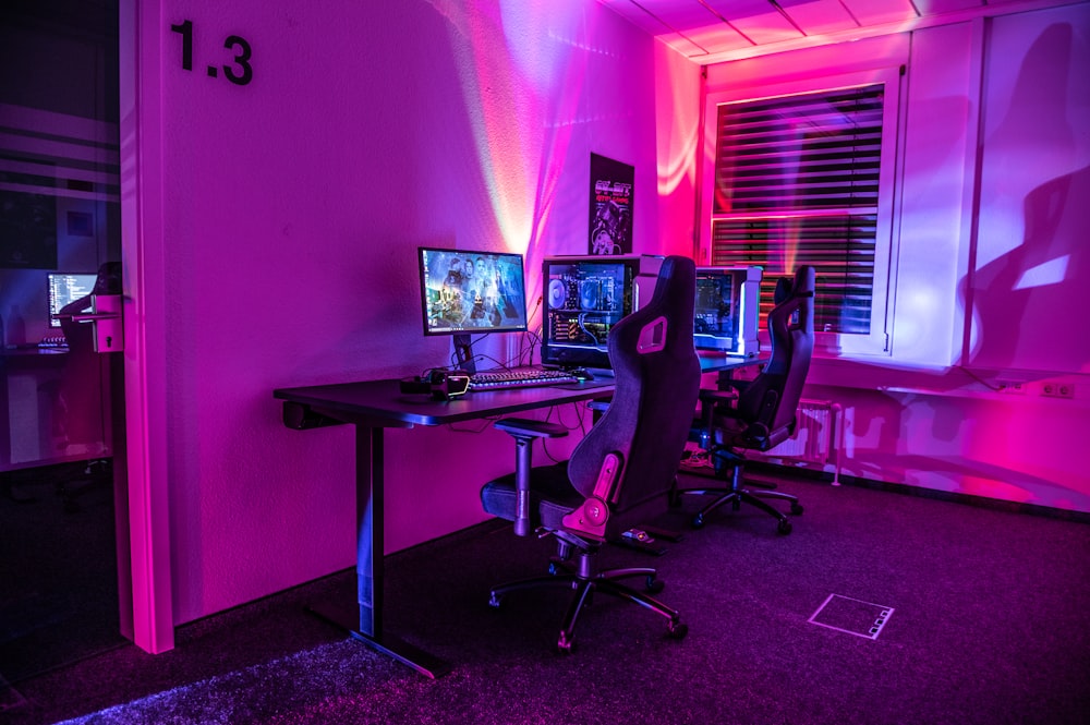 a room with a desk, computer, and two monitors