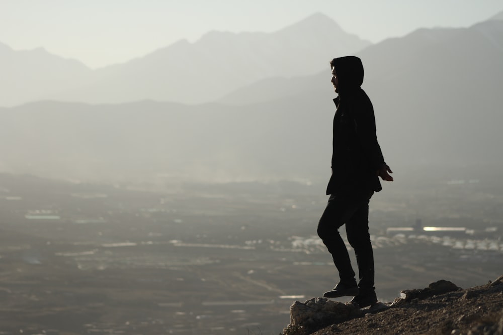 Un uomo in piedi sulla cima di una collina rocciosa