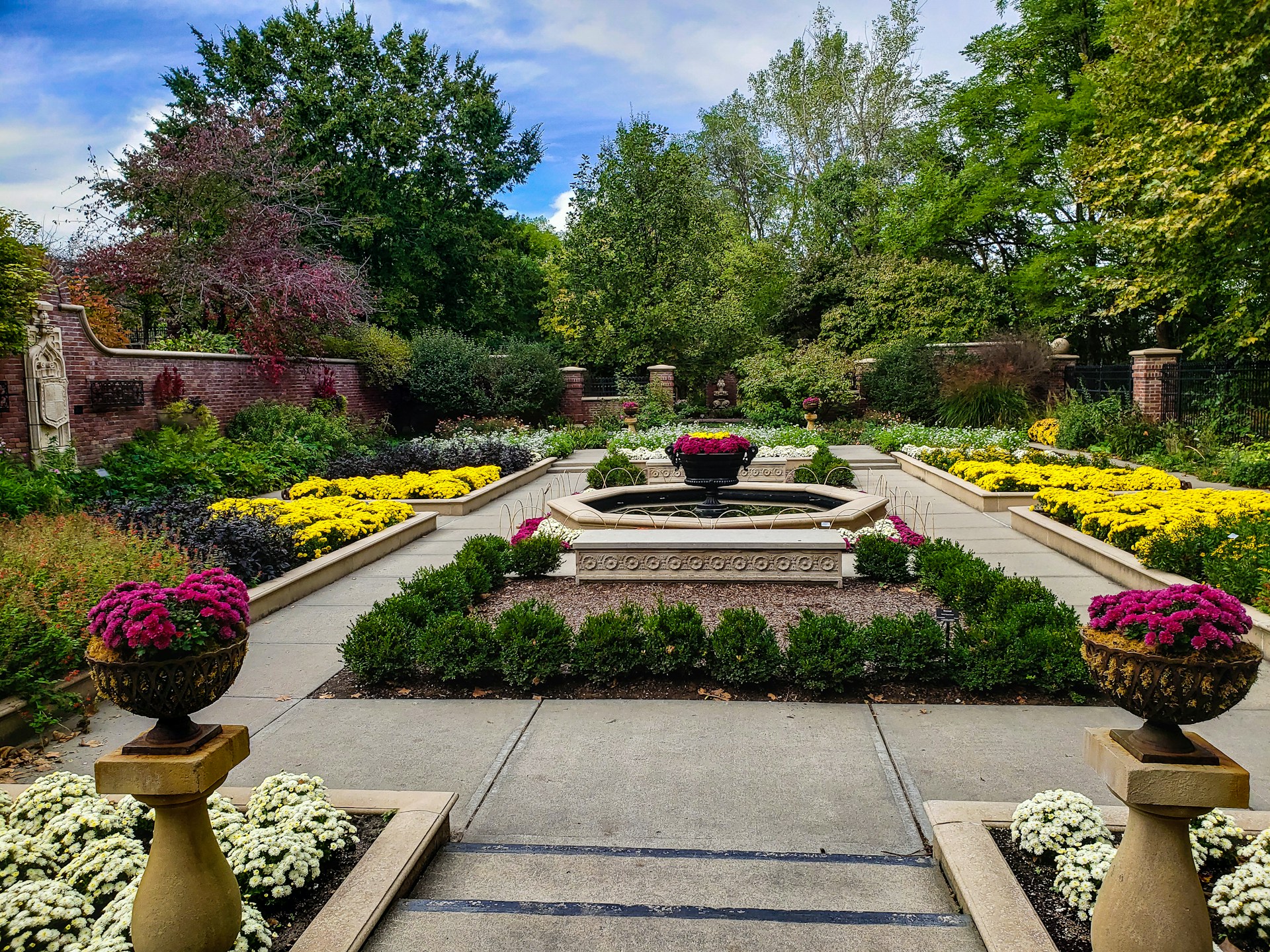 a garden with a fountain surrounded by flowers