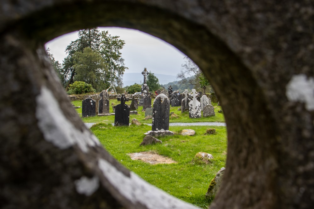 a view of a cemetery through a hole in a stone wall