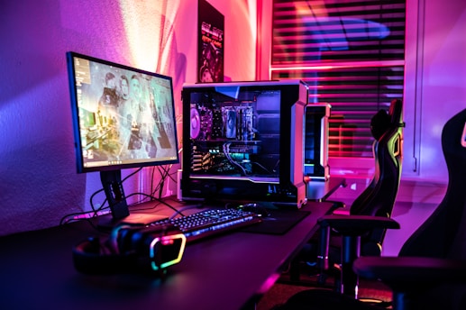 a computer desk with a monitor playing game, keyboard and mouse