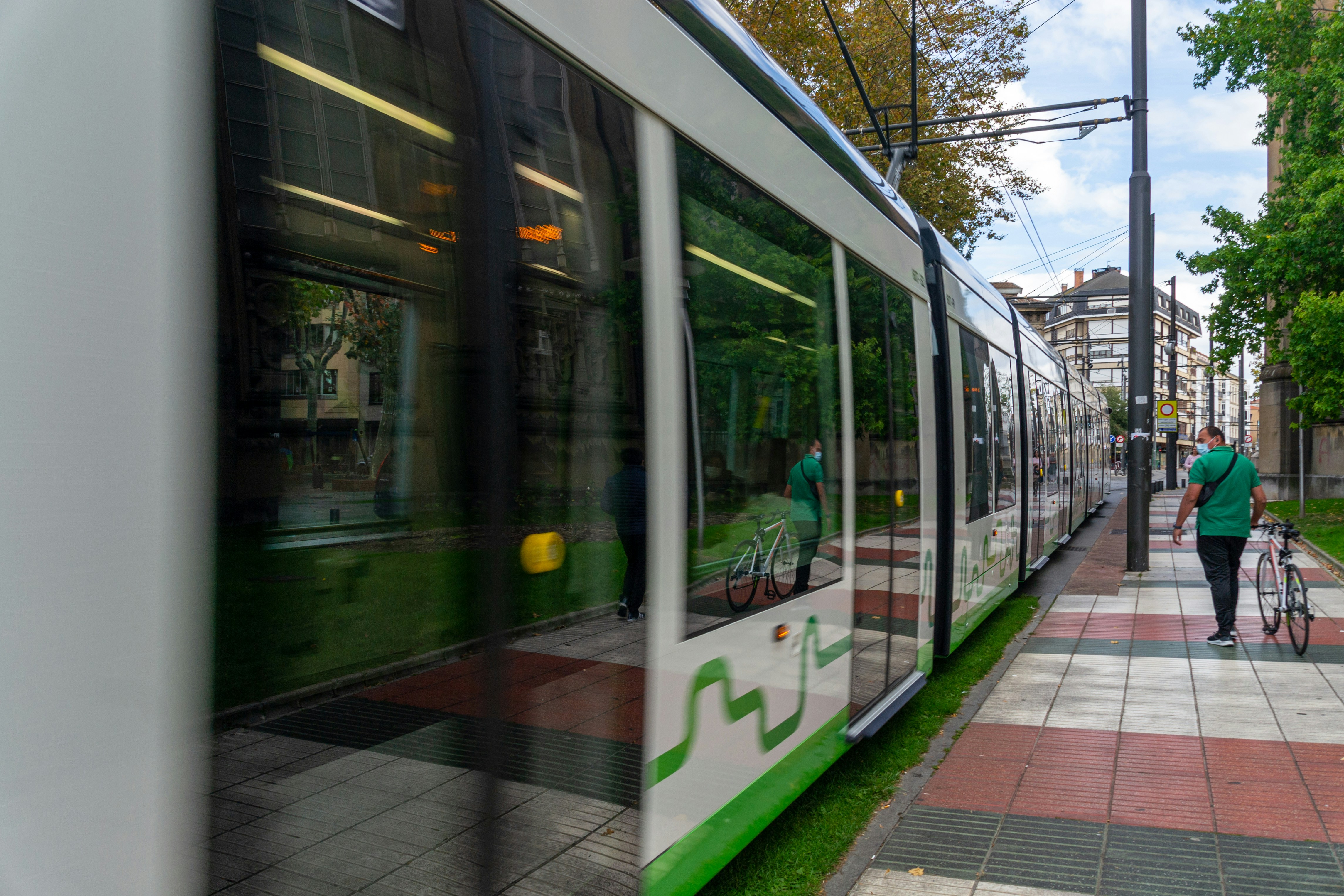 a person with a bike walking down a sidewalk next to a train