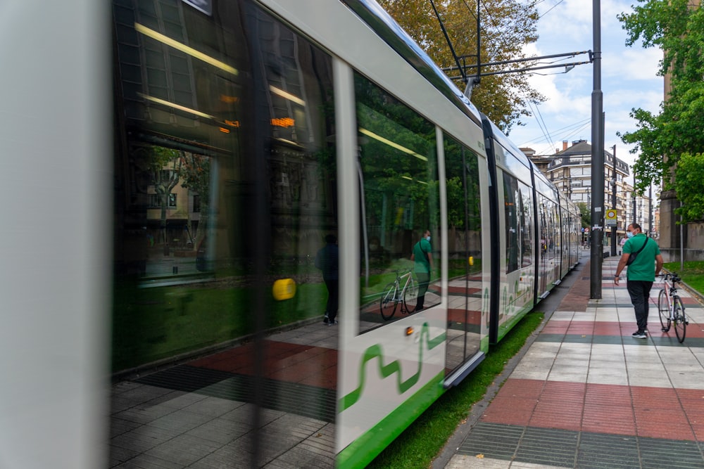 a person with a bike walking down a sidewalk next to a train